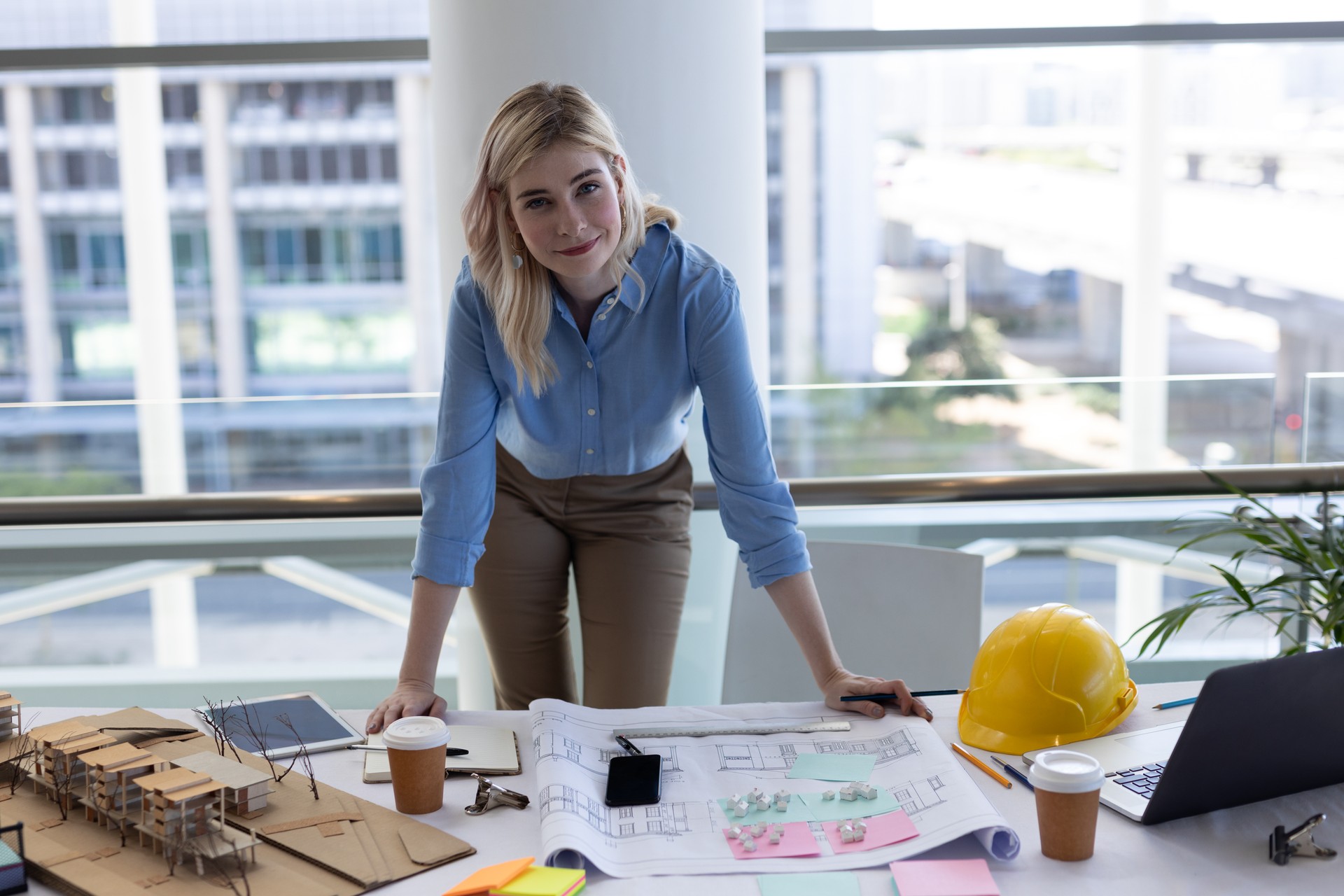 Blonde kaukasische Architektin schaut Kamera am Schreibtisch im Büro an